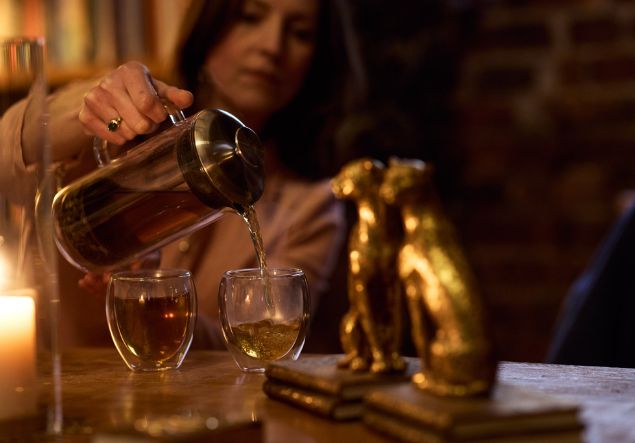 About 3 Tea is poured from a carafe into two glass mugs