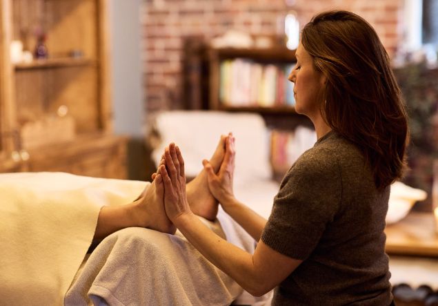 Womens wellness 4 A woman performs Reiki, holding palms to feet